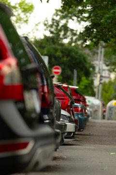 A line of parked cars is neatly arranged on a busy city street, showcasing modern parking techniques and essential street signs for guiding drivers and ensuring safe traffic flow