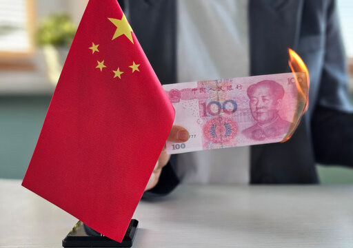 Person holding a burning Chinese 100 yuan bill near a Chinese flag