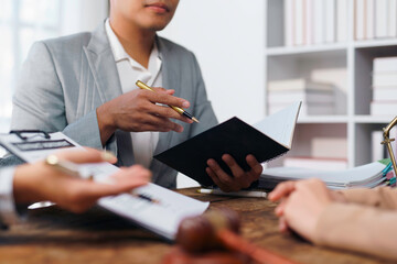 Fototapeta premium Lawyer holding agenda and pointing with pen while explaining case details to client in law firm
