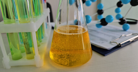 Lab experiment with bubbling yellow liquid in a flask next to test tubes and a molecular model...