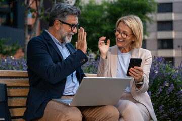 Business people, laptop and collaboration for research outdoor for website review and reading...