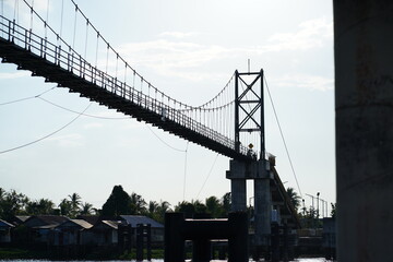 Suspension Bridge Spanning Over a River with Traditional Village Houses