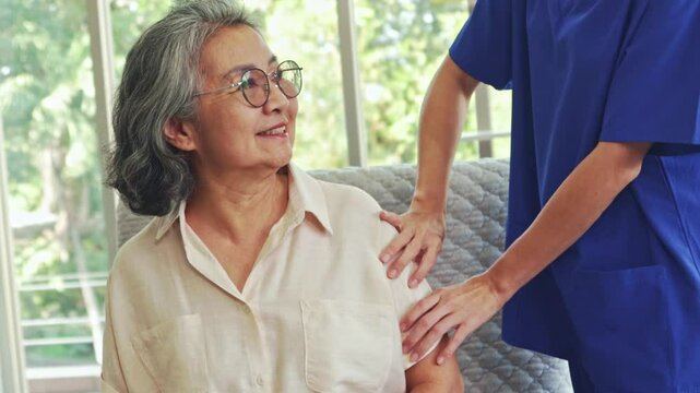 Female physiotherapist treats elderly woman with shoulder and arm pain. Nurse treats pain with relaxing massage, creating satisfaction for elderly woman in good mood.