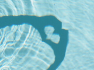 Selective focus. Hands creating a heart shape shadow in swimming pool.