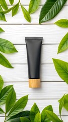 Black cosmetic tube surrounded by fresh green leaves on a white wooden surface texture