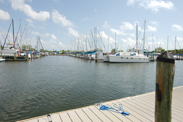 Fototapeta premium Tranquil Marina with Boats Moored Under a Clear Blue Sky. Gulfport, FL. Boats and yachts moored peacefully, under a bright blue sky with wispy white clouds, exemplifying a coastal lifestyle and scenic
