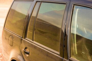 Dust-covered black car parked outdoors.
