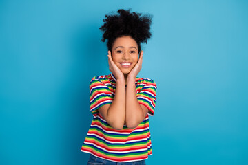 Beautiful young woman in casual striped t-shirt smiling and posing playfully against a solid...