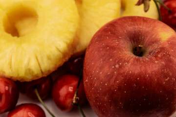 pineapple rings, red cherries, and a red and yellow apple are artfully arranged, healthy and appealing produce. Ideal for themes of wholesome eating, summer refreshments, and natural food beauty