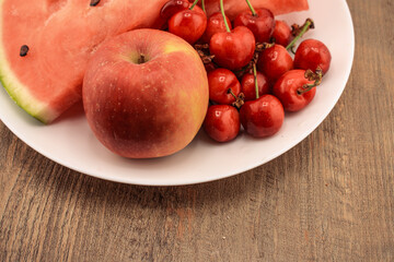 a watermelon slice, a crisp red apple, and a cluster of red cherries, presented on a wooden background.  for themes of wholesome eating, fresh produce, and natural snacks.
