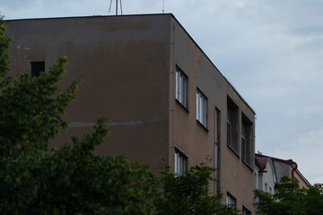 This captivating contemporary building, with its large windows, is surrounded by vibrant greenery and a cloudy sky, creating a delightful atmosphere that enhances its modern architecture