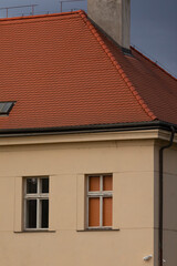 The facade of a visually striking building prominently features a vibrant red tiled roof along with a multitude of windows, showcasing intricate architectural elements and thoughtful design