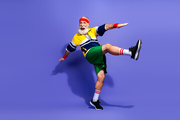 Energetic senior man in colorful retro sportswear striking a dynamic pose on a vibrant background