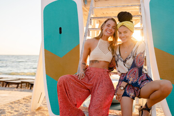 two stylish beautiful women relaxing having fun on beach in summer fashion trend outfit