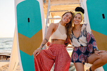 two stylish beautiful women relaxing having fun on beach in summer fashion trend outfit