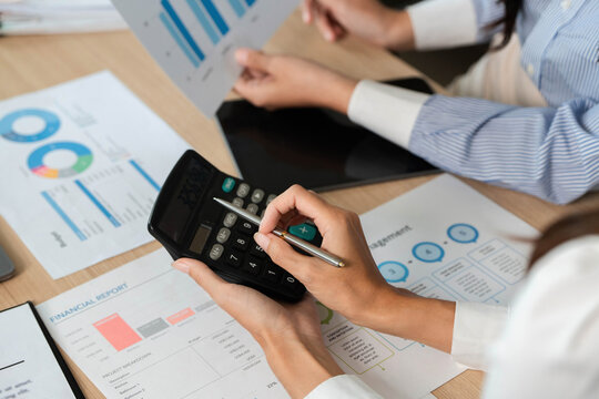 Calculating Financial Metrics. Professionals using a calculator for financial analysis and reports.
