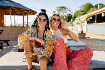 two stylish beautiful women relaxing having fun on beach in summer fashion trend outfit
