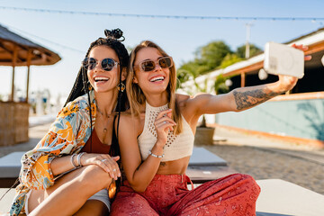 two stylish beautiful women relaxing having fun on beach in summer fashion trend outfit