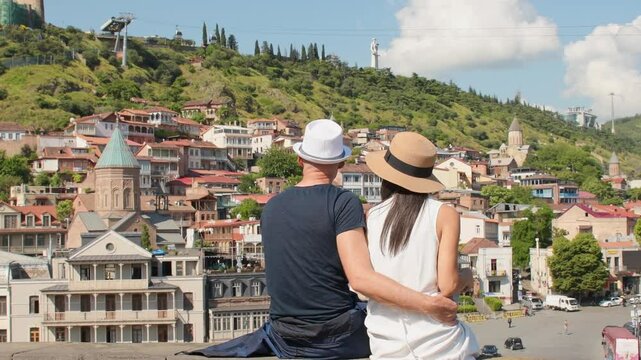 Couple of tourists in street hug enjoy beautiful Tbilisi old city colorful buildings at holidays in Georgia, caucasus. Romantic couple get away together on summer vacation .People and holidays concept