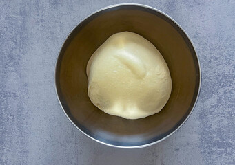 Smooth pizza dough resting in bowl, ready for homemade baking.