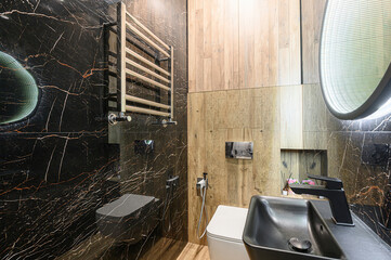 Stylish bathroom featuring black marble walls, light wood accents, modern fixtures including a...