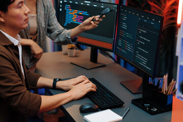 IT developers discussing with point to intelligent website development coder system running data...