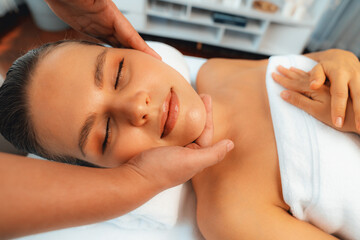 Caucasian woman enjoying relaxing anti-stress head massage and pampering facial beauty skin recreation leisure in dayspa modern light ambient at luxury resort or hotel spa salon. Quiescent