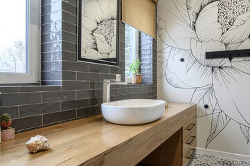 Stylish bathroom featuring a wood countertop, white sink, dark gray tiles, and a flower mural wall