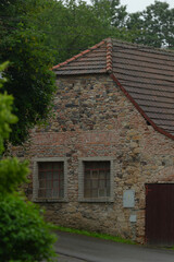 A charming stone structure with inviting windows and a striking red roof is thoughtfully nestled in a vibrant natural setting, creating an idyllic scene for all to enjoy