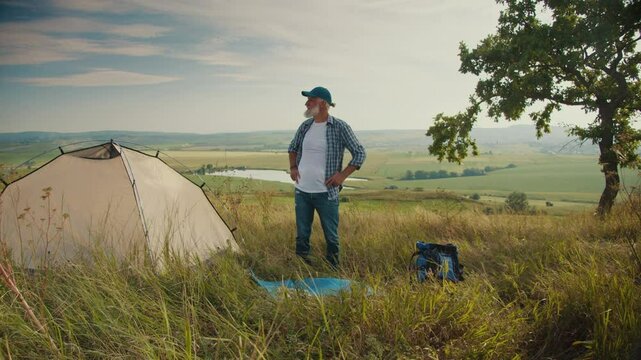 Active Aging, Vital Longevity. Senior Man Stands Beside His Tent, Admiring a Stunning Natural Landscape. A Peaceful, Inspiring Moment of Strength, Freedom, and Wellness After Retirement