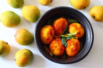 Peeled ripe mangoes in an earthen pot, scattered with chili powder and spices, prepping for Kerala curry with coconut and curd