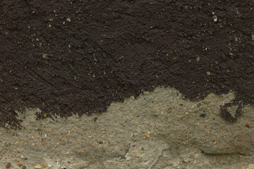 The image provides a closeup of soil texture, highlighting the contrasting dark and light sections that reveal the intricate composition and layering of earth beneath the surface