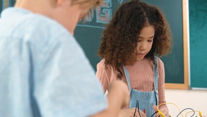 Girl standing while fixing electronic board by using screwdriver. American student and happy...