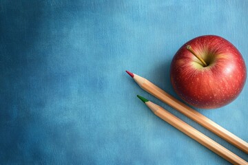 A red apple rests beside two colored pencils on a textured blue surface