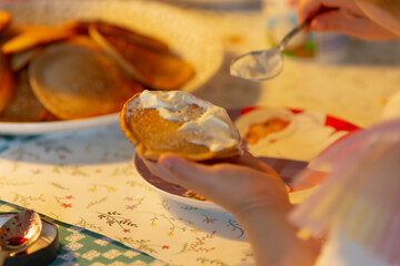 A small child joyfully holds a colorful bowl of dessert, using a shiny spoon to serve from a larger dish on a lovely kitchen table, capturing a warm family dining moment