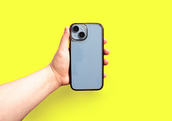 Dirty transparent phone case displayed on smartphone in hand, on vibrant yellow backdrop. Horizontal