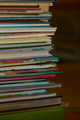 A vibrant stack of colorful magazines on a rustic wooden surface captures attention and inspires creativity with their artistic designs, perfect for igniting imagination