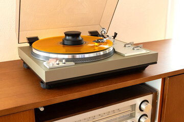 Vintage Stereo Turntable Record Player With Colored Disk and Weight Clamp Sitting on Wooden Console Cadenza Closeup