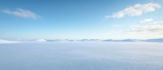 Fototapeta premium Expansive, serene vista of a snow-covered plain under a pale blue sky, sparsely dotted with wispy clouds