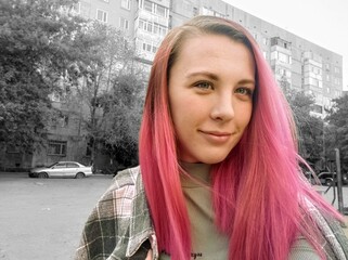 Portrait of a young beautiful girl with pink hair in the city