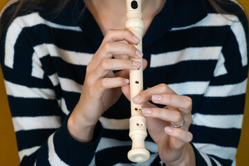 Close-up of female musician's hands delicately holding and playing a recorder flute, showcasing...