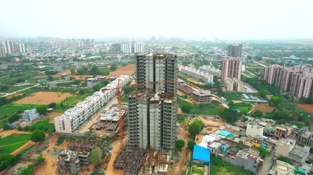 aerial drone shot orbiting under construction building with crane surrounded by smaller houses and independent homes showing the development of the city