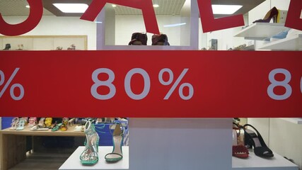 Sale signs and the words "80%" on the glass of a clothing store. Sale of branded clothing.
