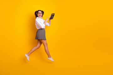 Young student posing with a calculator against a vibrant yellow background while expressing joy and...