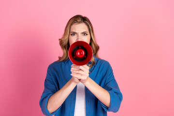 Obraz premium Confident young woman holding a red megaphone against a pink background, expressing strong emotion, dressed in a casual yet stylish outfit.