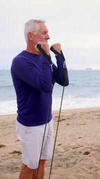 A mature 66 year old man exercising at the beach in Southern California. Vertical Video.
