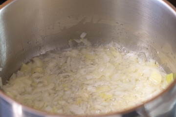 Chopped onions are fried with spices in a pot for preparing goulash