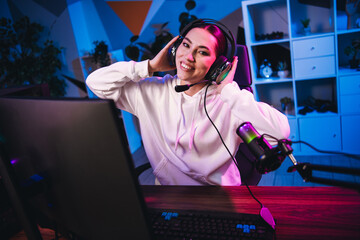 Young woman gamer streaming esports live with vibrant neon lights, enjoying online gaming from home...