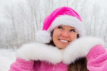 Girl in a pink Christmas hat in a winter forest