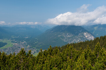 Hiking above the clouds on Wankberg, Germany—panoramic views of snow-capped Alps and lush valleys under a bright blue sky.